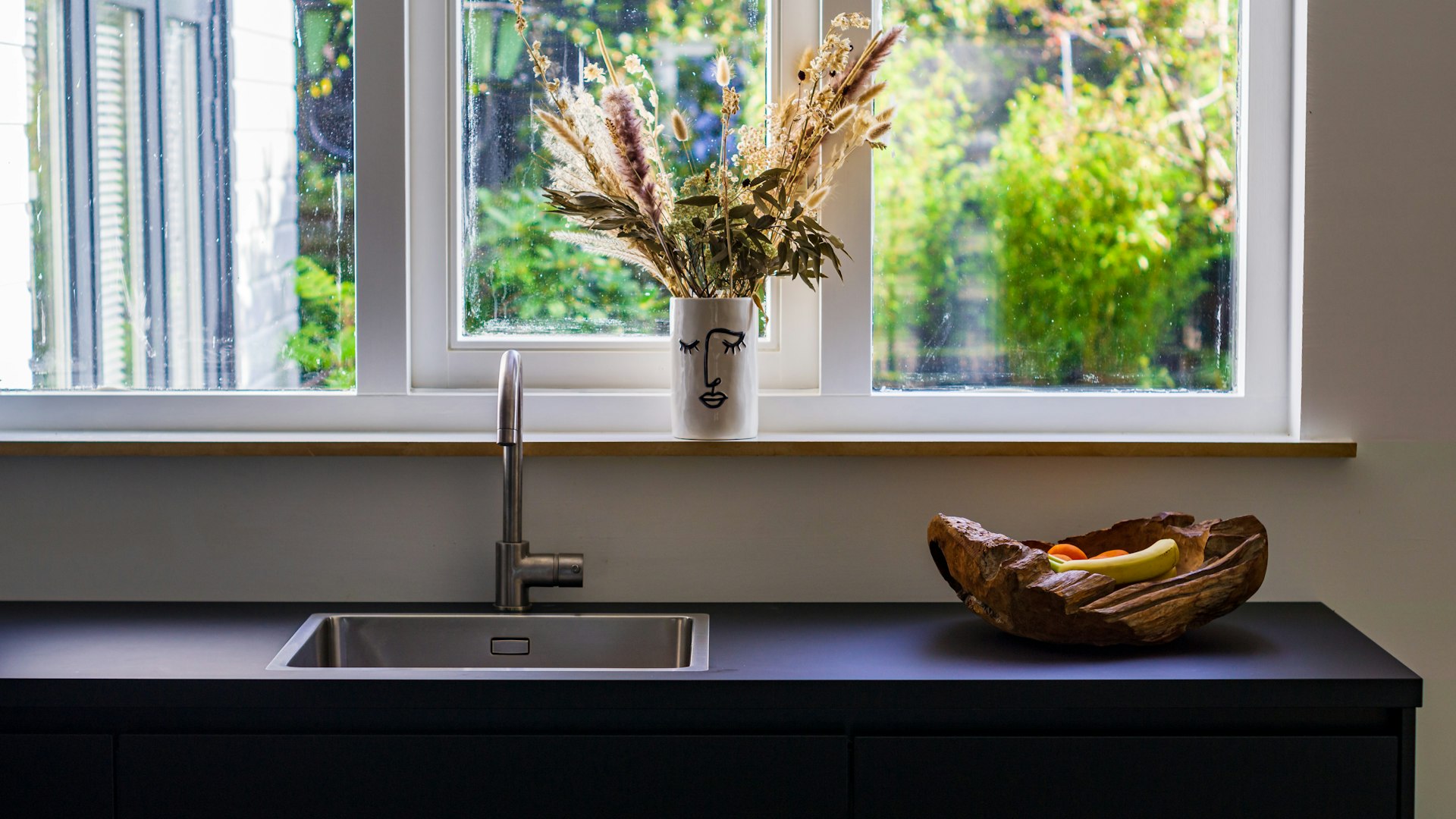 a bowl of fruit sitting on a counter next to a window
